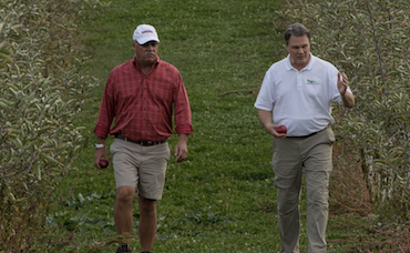 Image of 2 man walking down a field while talking.